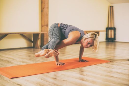 Woman doing yoga Astavakrasana/Eight Angle Pose.Toned image.