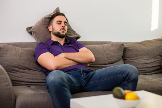 Man fell asleep while  while sitting on sofa  in his living room.