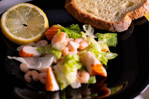 seafood salad composition with shrimps and surimi with cutlery and glass of white wine and lemons