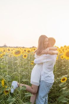 Autumn nature. Love and romance. Young romantic couple hugging in sunflower field in sunset