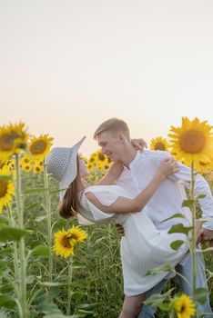 Autumn nature. Young romantic couple walking in sunflower field in sunset