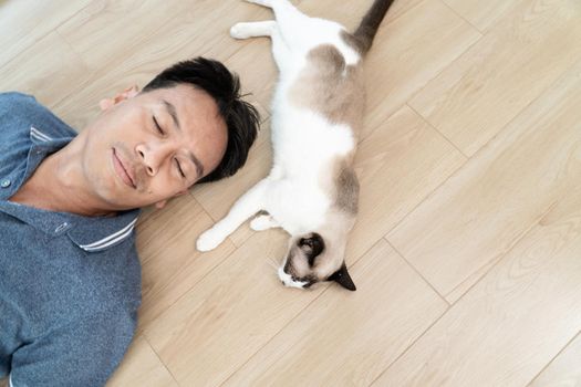 Asian man with elder cat lying on floor at home