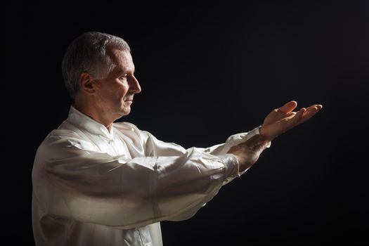 Senior man enjoys exercise Tai Chi indoor.