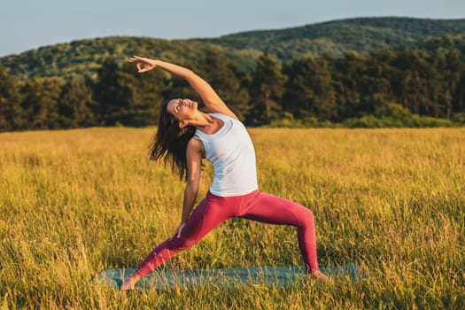 Beautiful woman doing yoga in the nature,Virabhadrasana/Warrior pose.