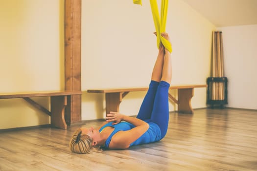 Woman doing aerial yoga in the fitness studio.Toned image.