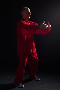 Senior man enjoys exercise Tai Chi indoor.