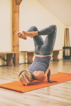 Woman doing yoga Vrschikasana/Scorpion pose.Toned image.