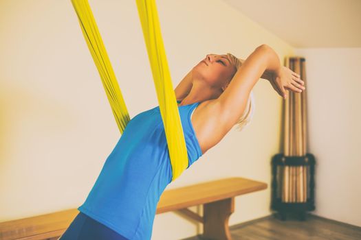 Woman doing aerial yoga in the fitness studio.Toned image.