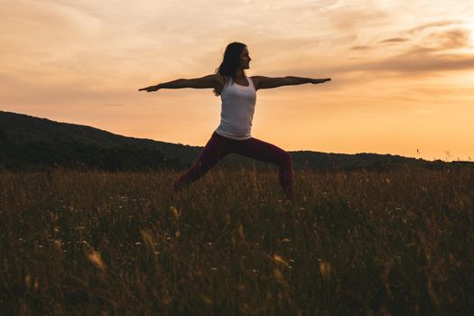 Silhouette of a woman practicing yoga/Virabhadrasana,Warrior Pose.