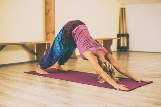 Woman doing yoga Adho Mukha Svanasana/Downward facing dog pose.Toned image.