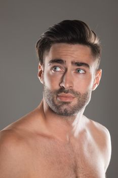 A portrait of a handsome naked man on gray background skin care model