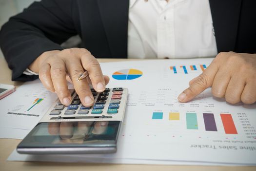 Asian accountant working and analyzing financial reports project accounting with chart graph and calculator in modern office, finance and business concept.