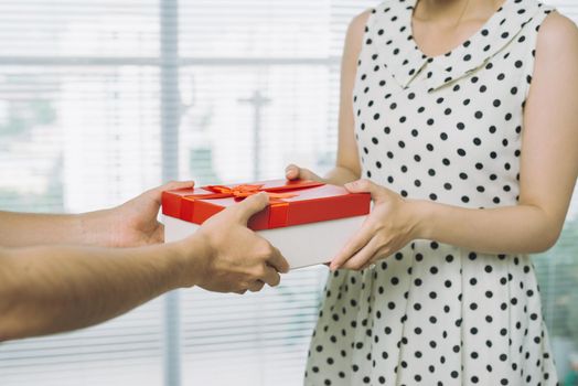 Man hand giving red gift to woman