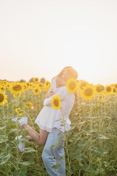 Autumn nature. Young romantic couple walking in sunflower field in sunset