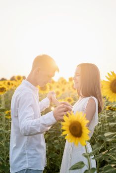 Autumn nature. Young romantic couple walking in sunflower field in sunset