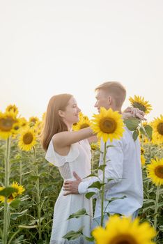 Autumn nature. Love and romance. Young romantic couple hugging in sunflower field in sunset