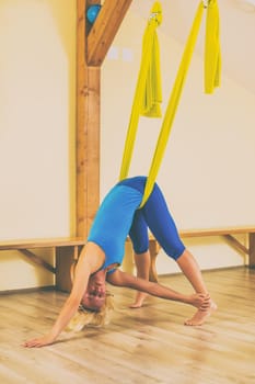 Woman doing aerial yoga in the fitness studio.Toned image.