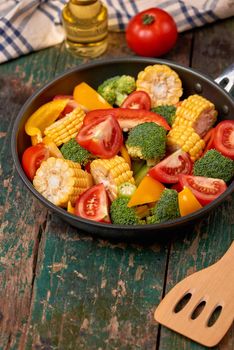 Fresh fruits and vegetables on a frying pan on an old wood background