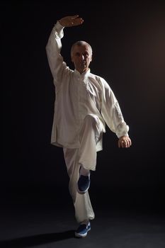 Senior man enjoys exercise Tai Chi indoor.