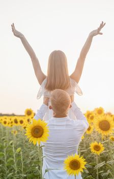 Autumn nature. Young romantic couple walking in sunflower field in sunset