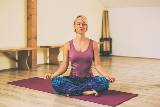 Woman doing yoga Padmasana/Lotus position.Toned image.