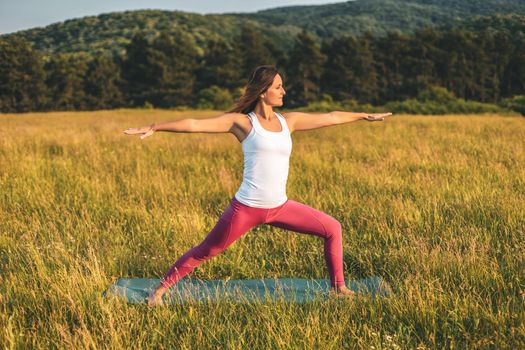 Beautiful woman doing yoga in the nature,Virabhadrasana/Warrior pose.