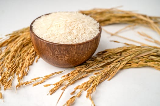 Jasmine white rice in wooden bowl with gold grain from agriculture farm.