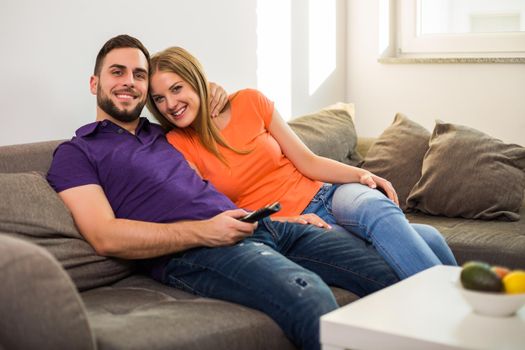 Happy couple enjoy watching tv and spending time together at their home.