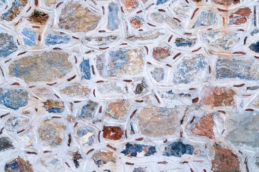 Background texture of wall made of colored stones with white putty.
