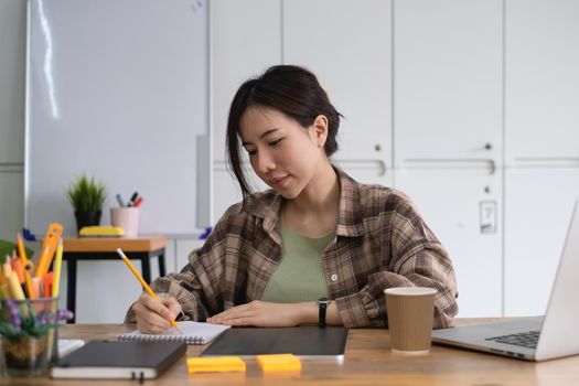 Portrait of cheerful asian woman with casual life on desk in home office. Concept of young business people working at home