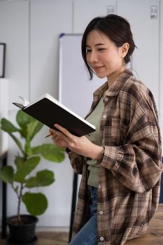 Portrait of cheerful asian woman with casual life on desk in home office. Concept of young business people working at home.