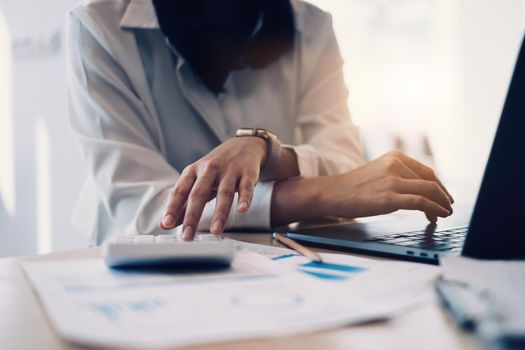 Close-up of a businesswoman using a calculator to audit the company's budget. Tax information is calculated by accountants