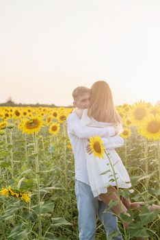 Autumn nature. Love and romance. Young romantic couple hugging in sunflower field in sunset