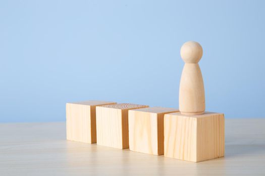 Career growth, development. Leadership, goal achievement. Wooden people figures on top of wooden blocks