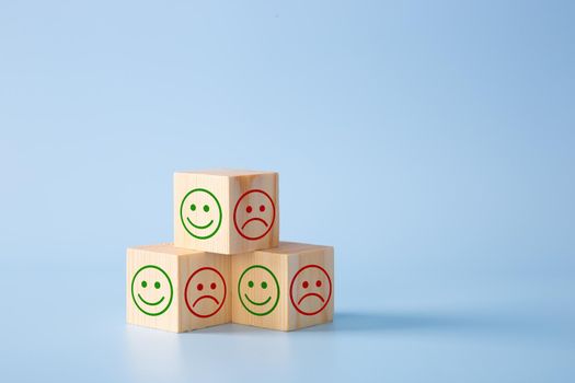 Wooden block With Happy and Unhappy Face on blue background