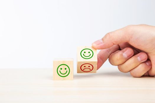 Hand turning a wooden block With Happy and Unhappy Face on white background