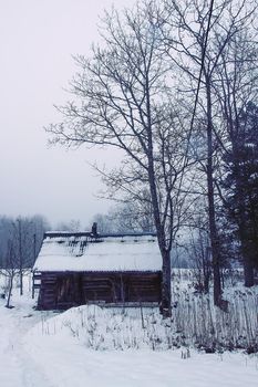 Old wooden building of bathhouse in the village in winter day. Traditional exterior oin Russian style.