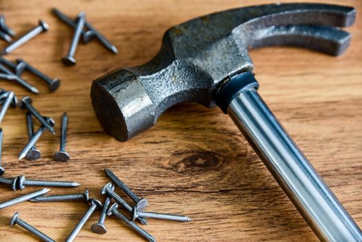 Metal hammer with nails on a wooden table. Close up. Carpenter concept.