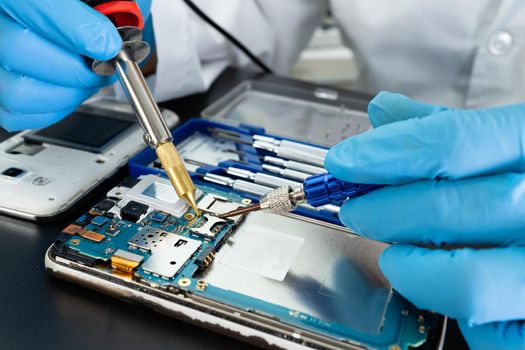 Technician repairing inside of mobile phone by soldering iron. Integrated Circuit. the concept of data, hardware, technology.