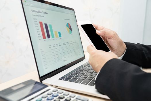 Asian accountant working and analyzing financial reports project accounting with chart graph, mobile phone and calculator in modern office, finance and business concept.