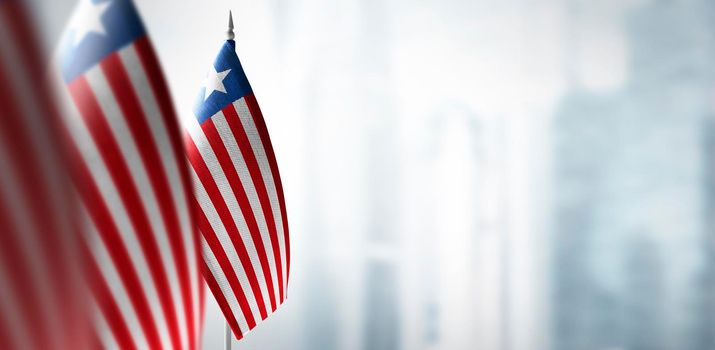 Small flags of Liberia on a blurry background of the city.