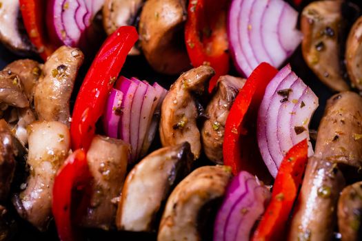 Close up of mushroom, red onion and red peppers kebabs