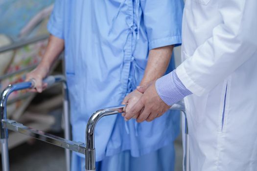 Doctor help Asian senior or elderly old lady woman patient walk with walker at nursing hospital ward.