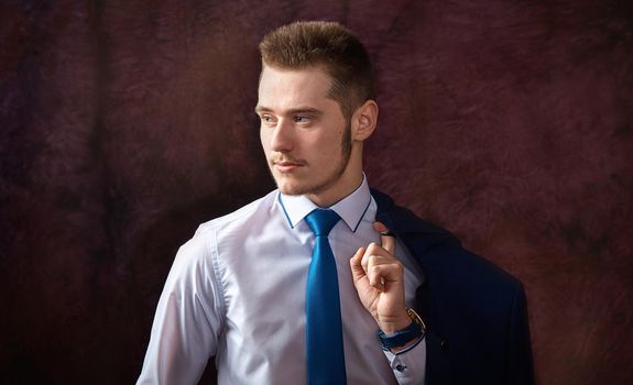 Portrait of a young man in white shirt holding jacket on shoulder