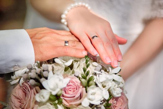 Bride and groom holding bridal bouquet close up