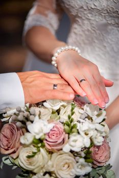 hands of groom and bride on a bouquet