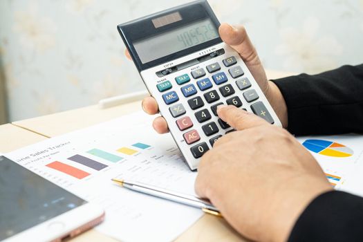 Asian accountant working and analyzing financial reports project accounting with chart graph and calculator in modern office, finance and business concept.