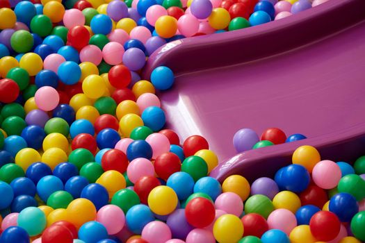 Dry children's pool with plastic slider and colorful balls.colored plastic balls in a children's playroom. background. texture