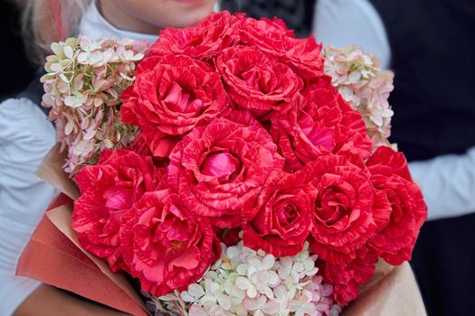 Bouquet of roses in the hands of a young girl
