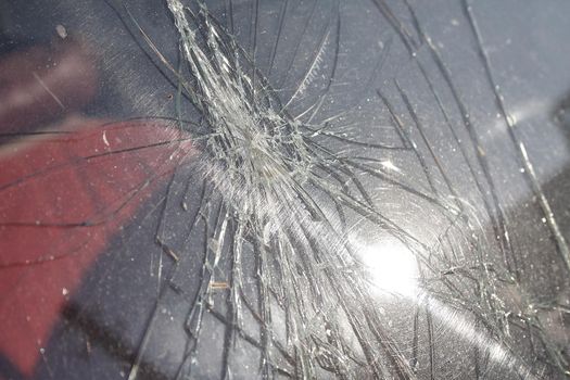 Cracks and glass shards radiate from the point of impact in a window that has been hit by an object